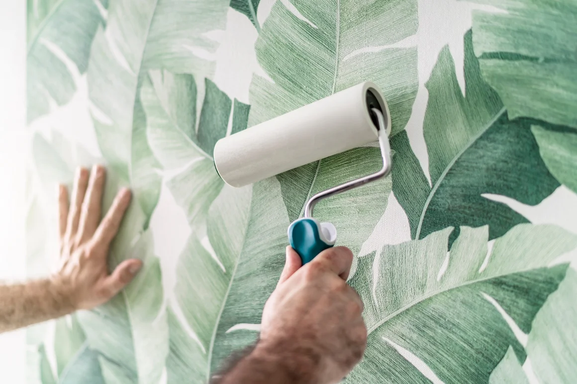 Person klebt Tapete mit Muster